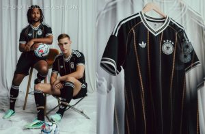 The black Germany 2026 Jersey featuring vertical gold diamond lines, white Trefoil logo, and four-star DFB badge.